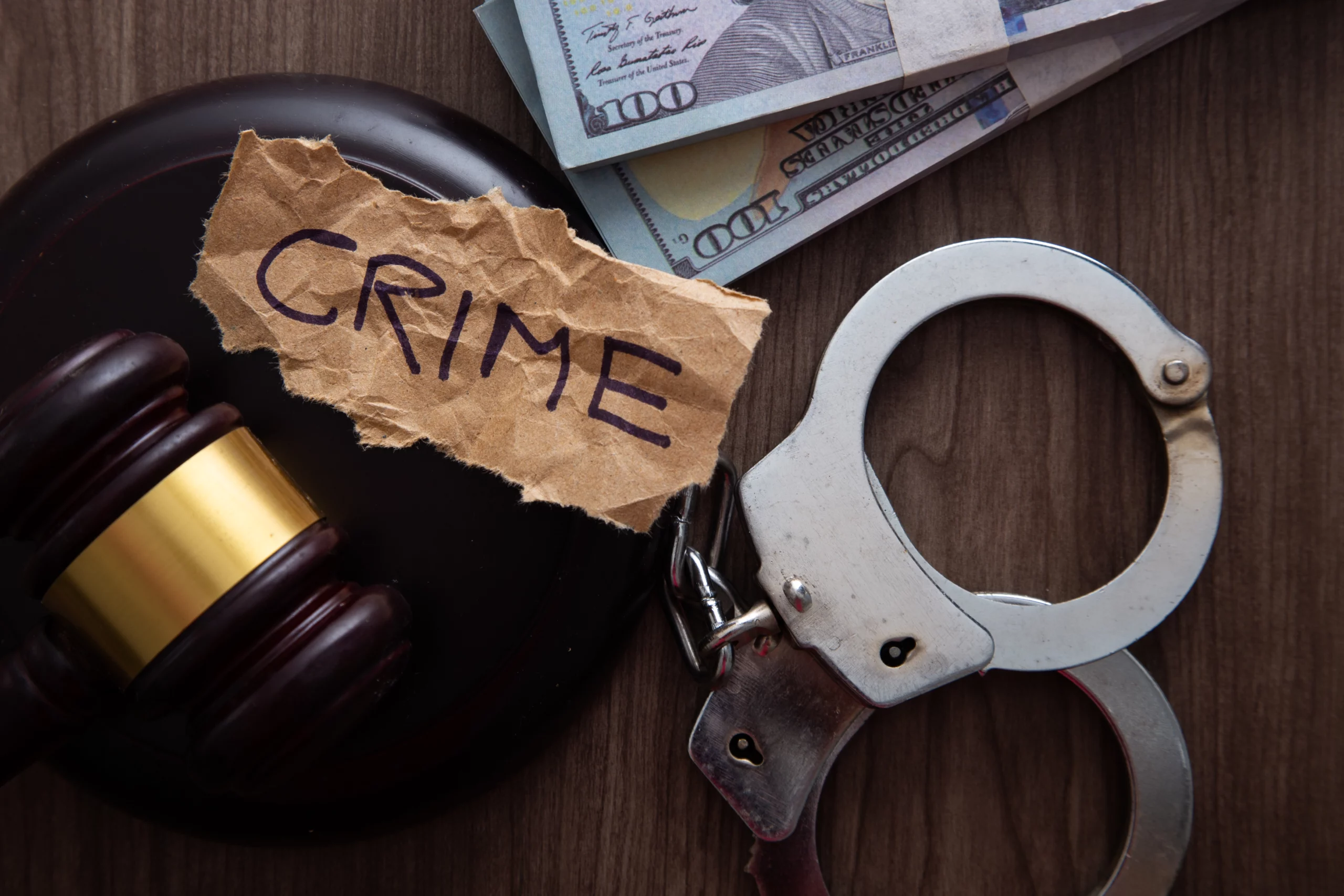 Gavel, handcuffs, cash, and torn “CRIME” paper symbolize felony charges in Indiana.
