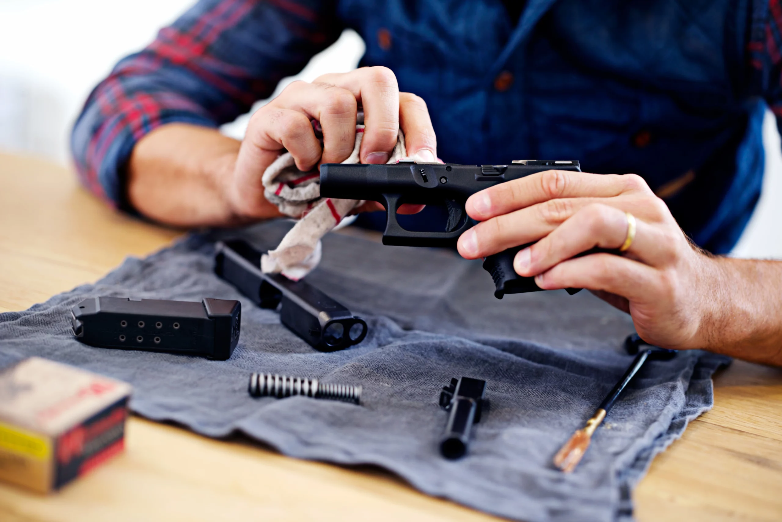 Person cleaning disassembled handgun parts on cloth representing Indiana zip gun legality, firearm possession law, and legal defense information