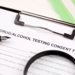 Drug and alcohol testing consent form on clipboard with pen and magnifying glass, representing probation drug test requirements and the serious legal consequences of failing a drug test