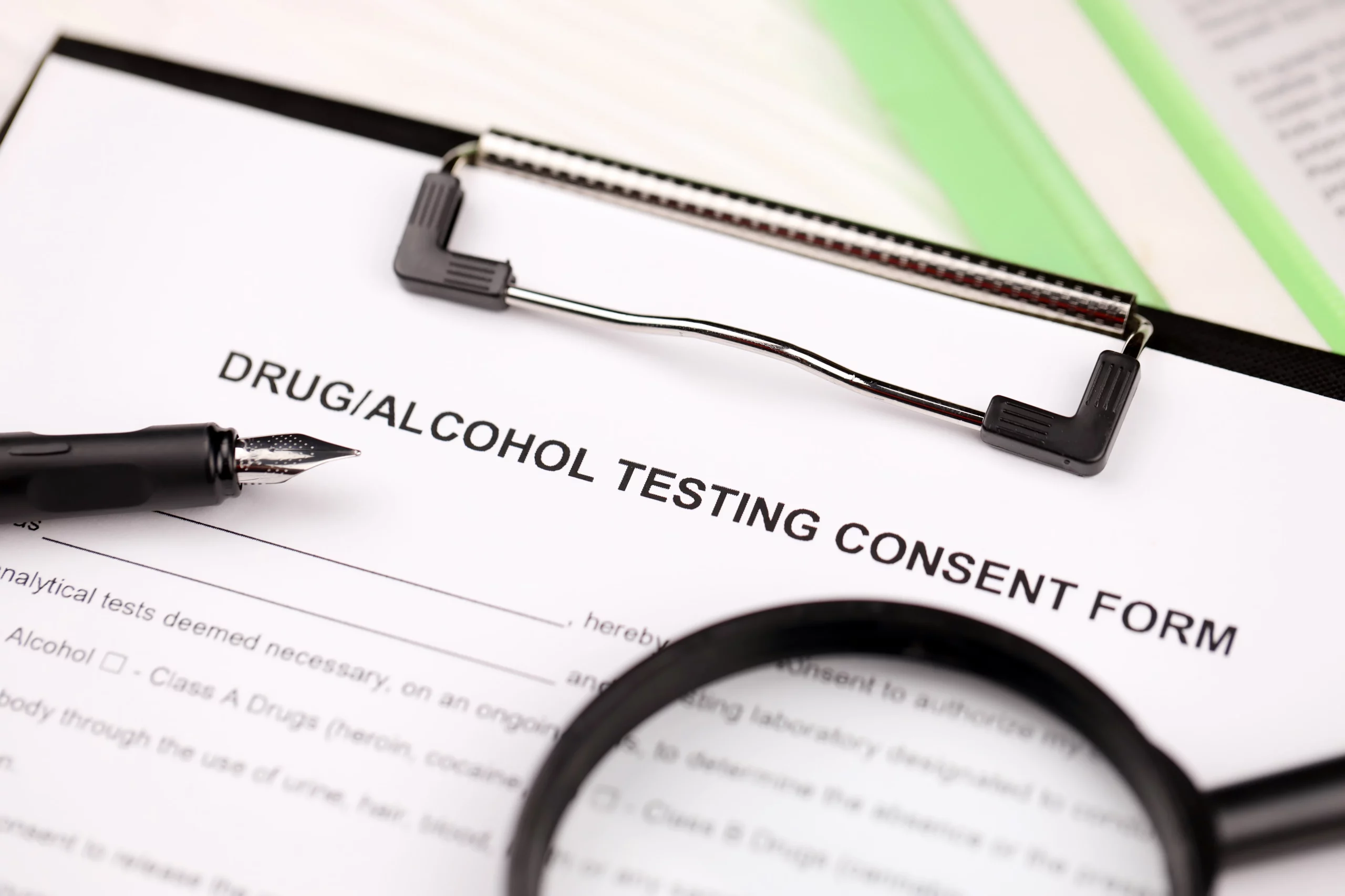 Drug and alcohol testing consent form on clipboard with pen and magnifying glass, representing probation drug test requirements and the serious legal consequences of failing a drug test