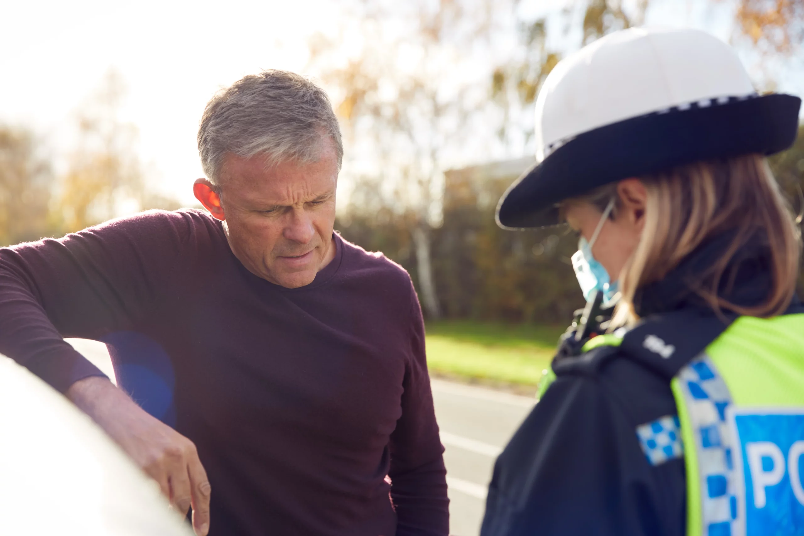 Concerned driver speaking with police officer after traffic stop, illustrating a stop-and-identify situation where officers may request identification and refusal could lead to legal consequences if lawfully detained.
