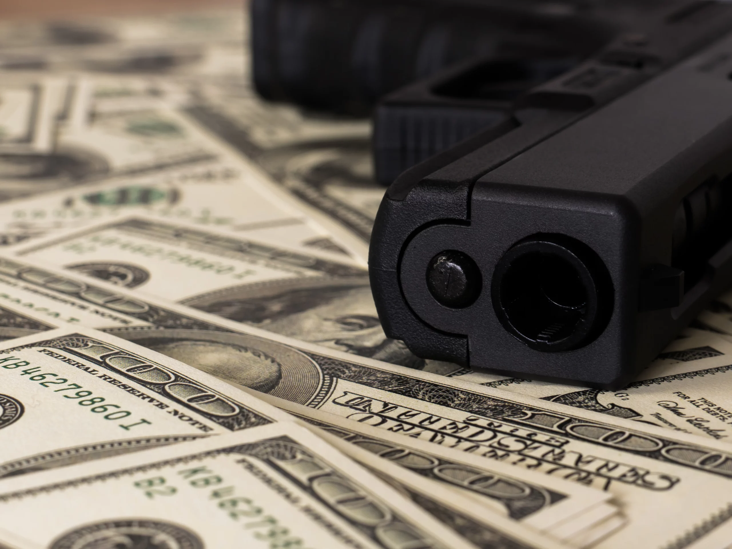Black handgun resting on U.S. currency, illustrating legal challenges involving no-knock warrants and police raids.