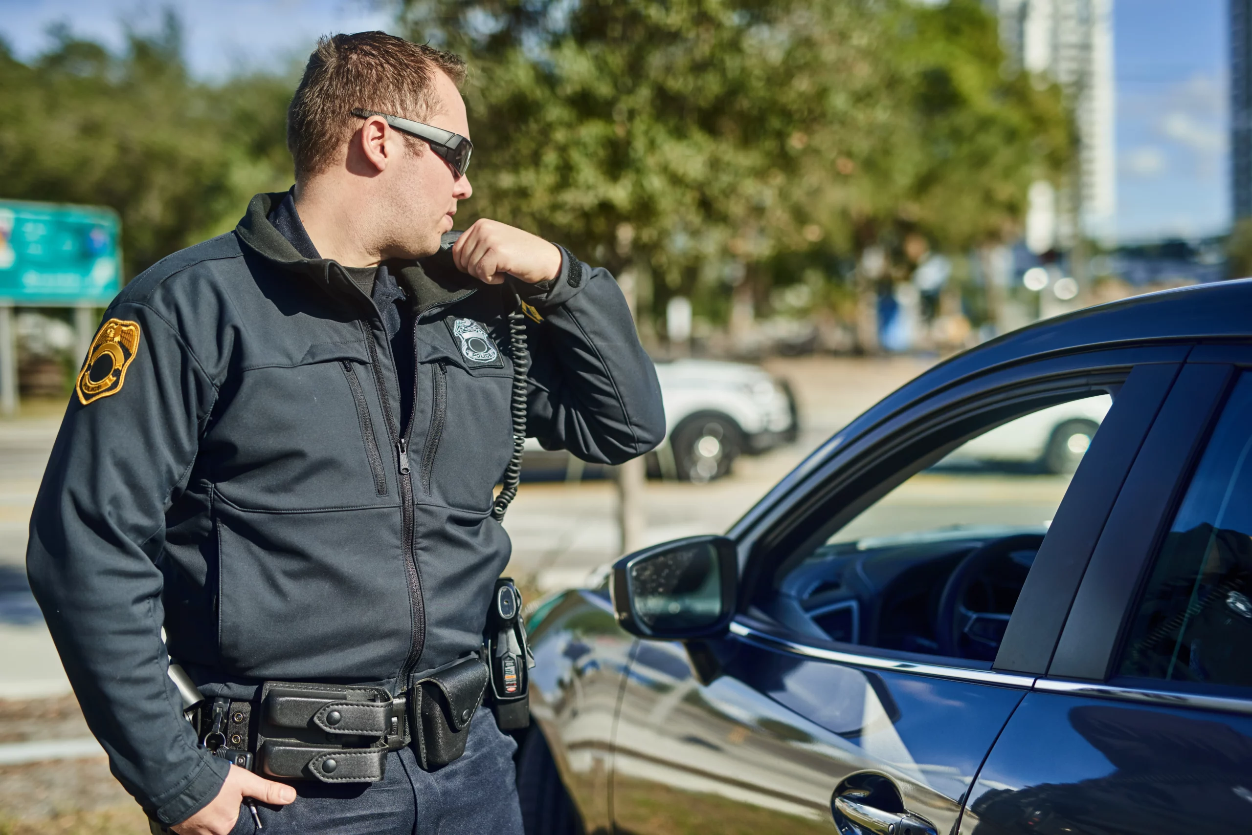 Police officer using a shoulder radio during a traffic stop, illustrating police searches of a vehicle glovebox in Indiana.